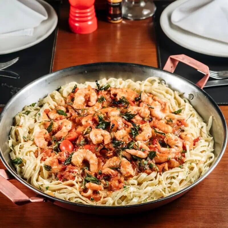 380g de Camarões Puxados no Azeite Extra Virgem, Alho e Cebola. Flambado com Vinho Branco, Aromatizado com Ervas de Provence, com Molho de Tomate Fresco, Molho Branco Eum Toque de Limão. Servido Sobre Fettuccine Italiano.