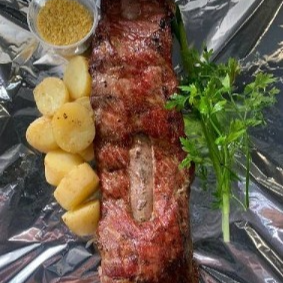 Costela Suína preparada na churrasqueira, acompanhada de uma deliciosa porção de batata no molho de alho e farofa.