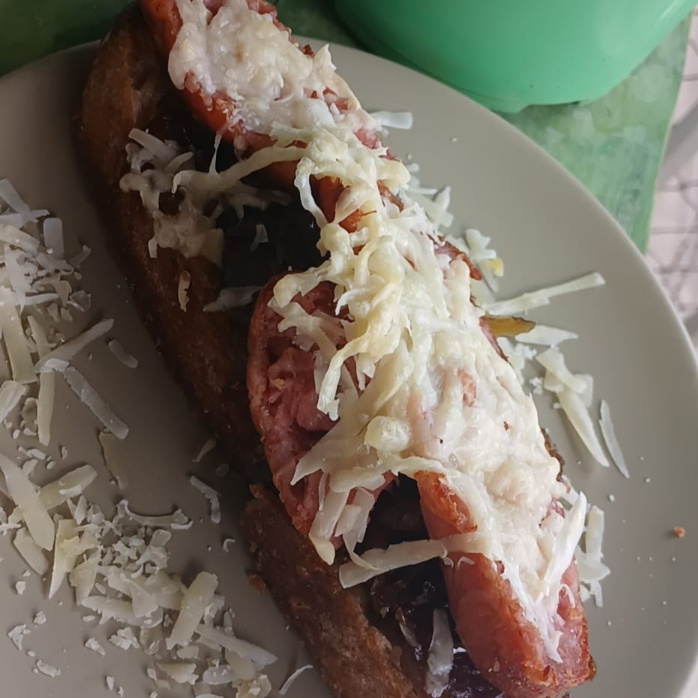 Fatia de Sourdough tostada na manteiga, cebola caramelizada, linguiça toscana grelhada e parmesão maçaricado