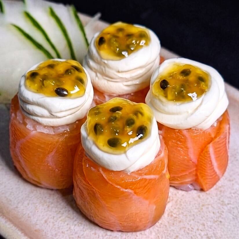 Enrolado de salmão com arroz, finalizado com cream cheese e polpa de maracujá.
