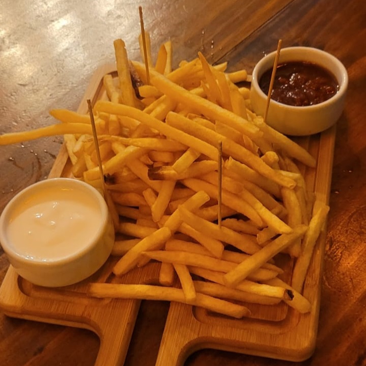 Fritas clássicas, acompanhada de ketchup e maionese artesanalmente preparados na casa, ideais para compartilhar.
