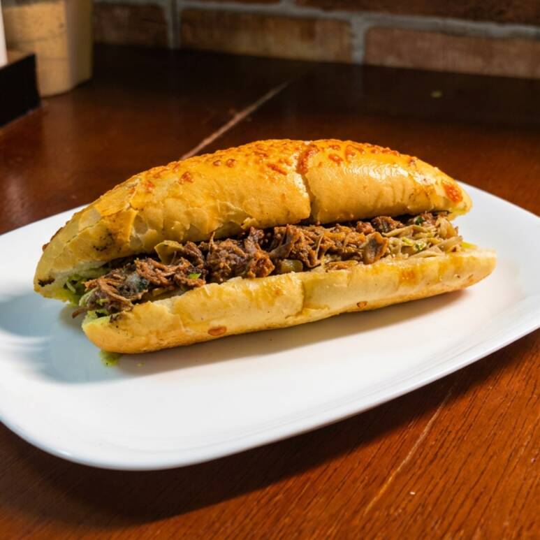 Baguete parmesão, deliciosa carne louca com mussarela e maionese da casa.