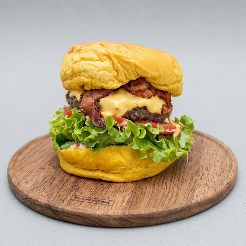 Maionese da casa, blend de hambúrguer artesanal de 200 gramas, american cheese, bacon crocante, rodelas de tomate, alface americana crocante no pão brioche.