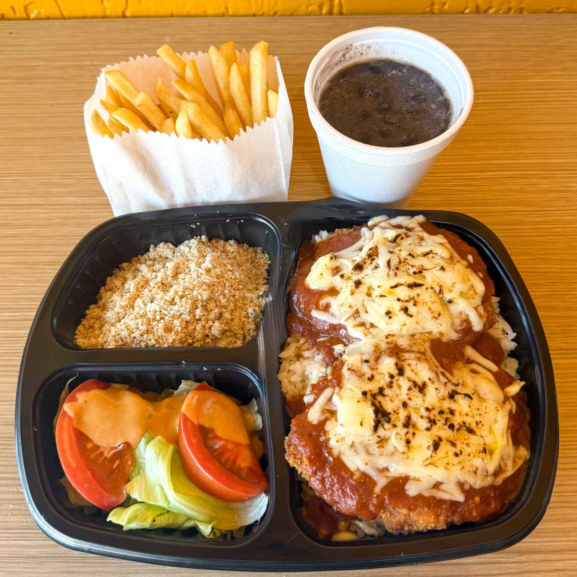 Frango empanado coberto com molho de tomate e queijo gratinado, acompanhado de arroz soltinho, feijão, batata frita, farofinha e salada. Sabor marcante e bem servido.