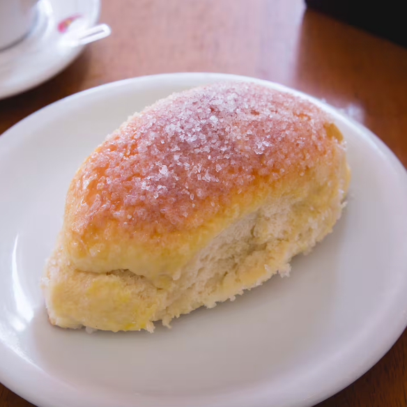 Massa doce, leve e macia, finalizada em duas versões irresistíveis: uma com cobertura delicada de açúcar e outra com creme suave e coco ralado fresco.