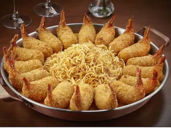 18 camarões empanados, recheados com queijo Catupiry, servido sobre cremoso arroz com camarão, ervilhas e presunto envolvido com molho branco. Gratinado com queijo mussarela. Acompanha batata palha.