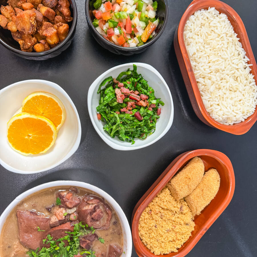 Feijoada embalada separadamente Acompanha: Arroz, Couve Refogada, Farofa, Torresmo, Banana a Milanesa, Vinagrete e Laranja.