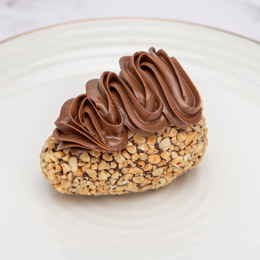 Morango inteiro envolvido por um brigadeiro cremoso, coberto com amendoim triturado e finalizado com uma generosa camada de creme de avelã.