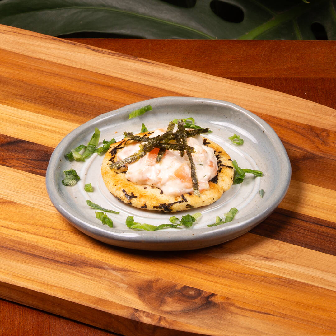 Tartare de salmão cream cheese com um toque de limão e dill, servido sobre um crocante biscoito de arroz e algas. Porção de 30g de salmão.