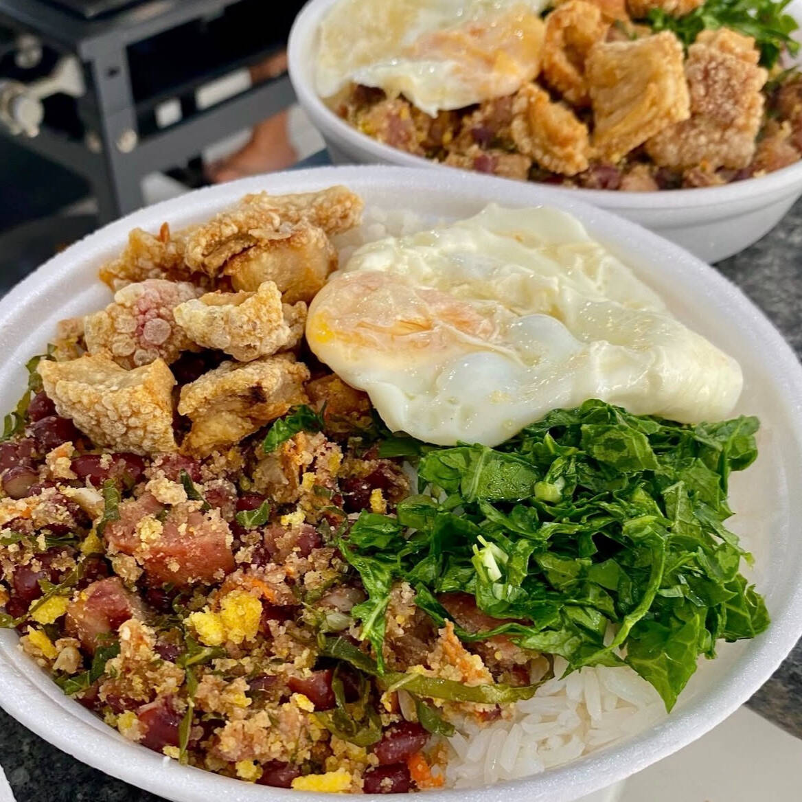 Feijão Tropeiro (500g) – Feijão de primeira com pernil picado, joelho de porco, calabresa, ovos, flocão de milho, farinha de mandioca, torresmos e couve refogada, finalizado com um ovo frito por cima. Serve até 2 pessoas.