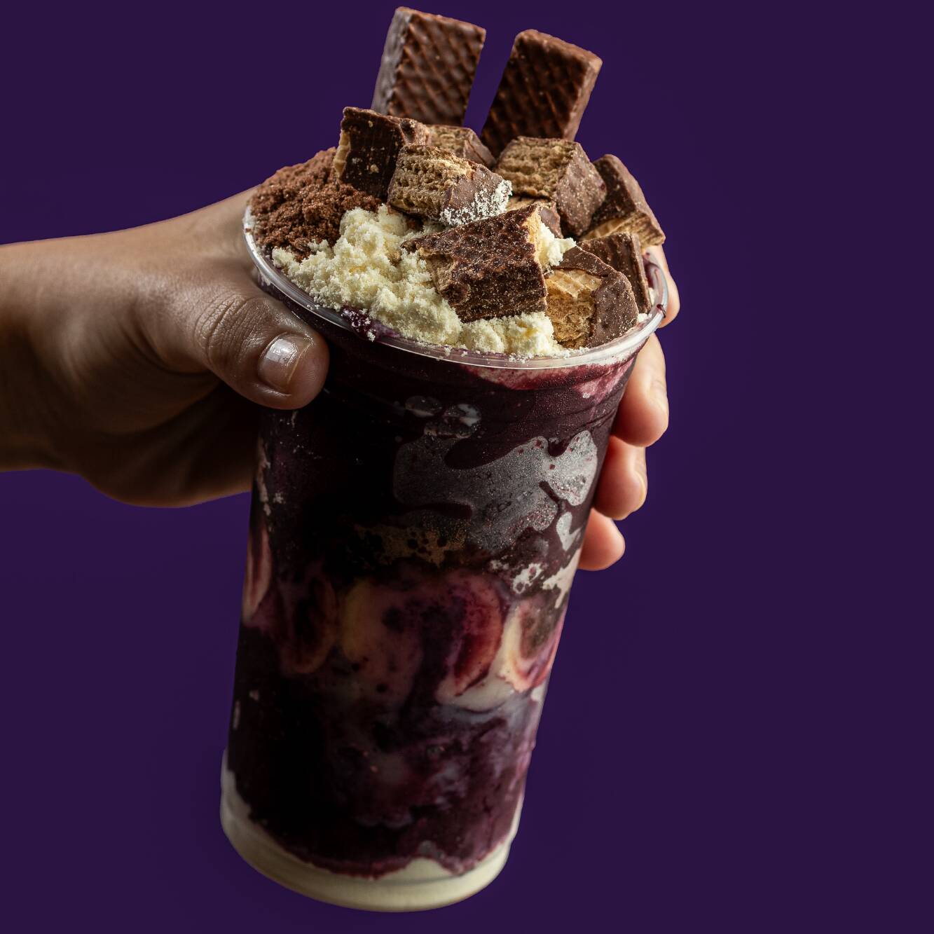 Creme de açaí acompanhado de banana, leite condensado, leite em pó, Ovomaltine e Bis no pote.