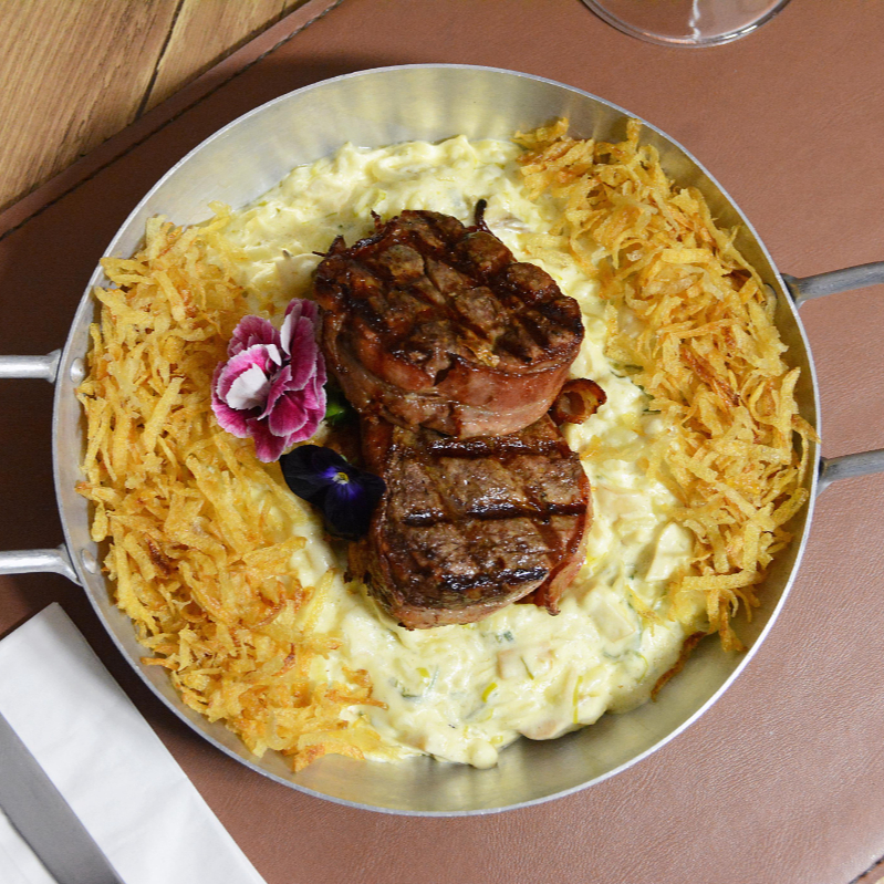 Filé mignon envolto no bacon com risoto de champignon, palmito e alho-poró finalizado com batata palha caseira.