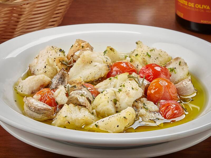 Bacalhau em lascas com azeite, alho, alecrim, tomilho e tomate cereja. Acompanha pão italiano.
