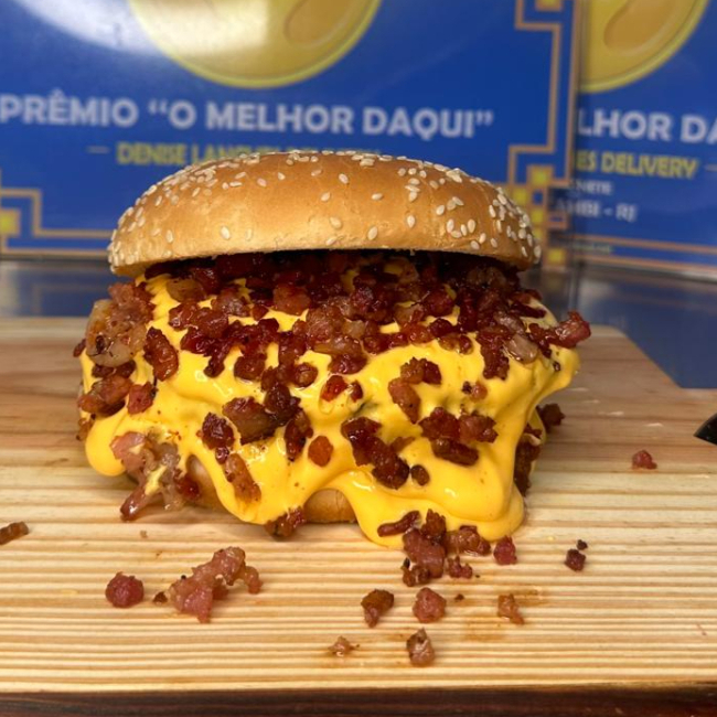 Pão, hamburguer de frango empanado, creme de cheddar e bacon em cubos.