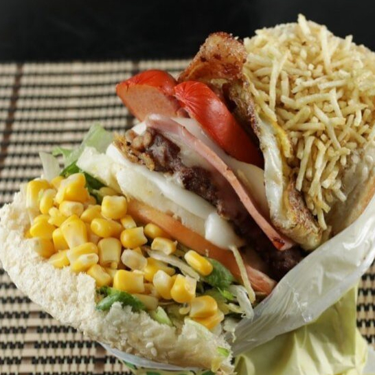 Carne Ao Ponto, Ovo Bem Servido, Salsicha Saborosa, Mussarela Derretida, Milho Doce, Batata Palha Crocante, Alface e Tomate No Pão Macio Que Satisfaz!