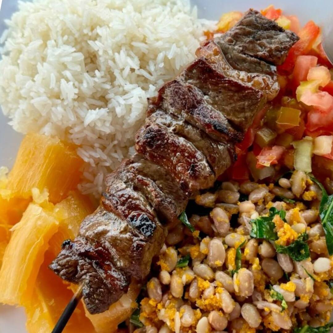 Espetinho de contra filé assado na brasa, arroz soltinho, feijão tropeiro com banana frita, mandioca cozida e vinagrete fresco. Marmitex completa e saborosa, ideal para o almoço. Serve 1 pessoa – Aproximadamente 650g.
