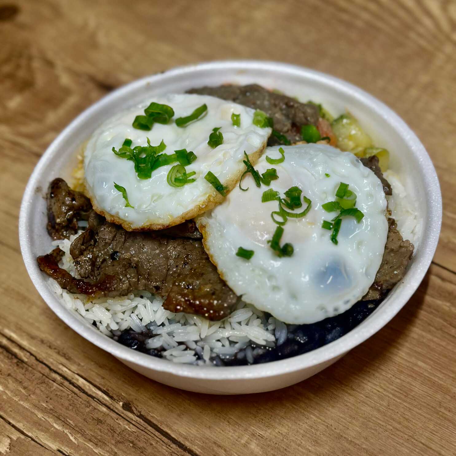 Bife grelhado suculento com 2 ovos fritos por cima, acompanhado de arroz, feijão caseiro, farofinha e legumes refogados. Prato reforçado, daqueles que sustentam o dia inteiro. Comida raiz, daquelas que a você adora