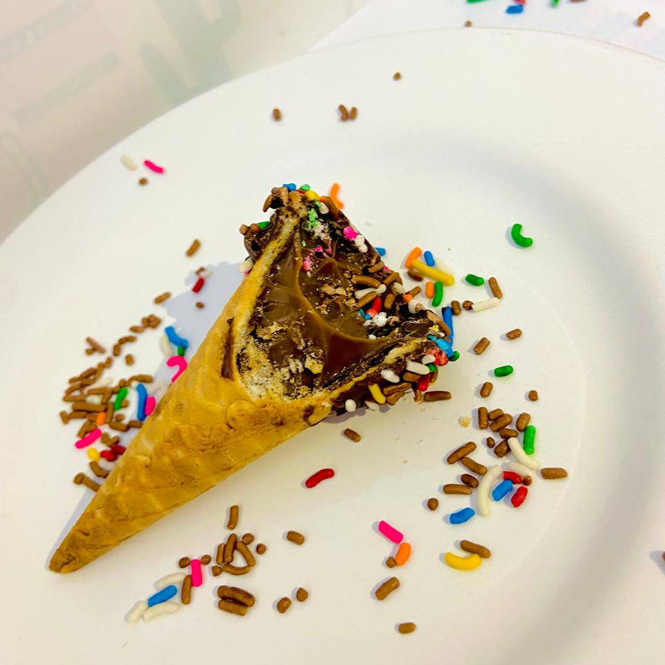 Cone com chocolate meio amargo por dentro, recheio de brigadeiro, finalizado com granulado colorido.