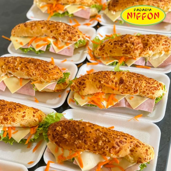 Baguete macia com cobertura de queijo parmesão, recheada com patê de frango cremoso, presunto, muçarela, alface fresquinha e cenoura ralada. Um sanduíche completo, saboroso e perfeito para um lanche caprichado!