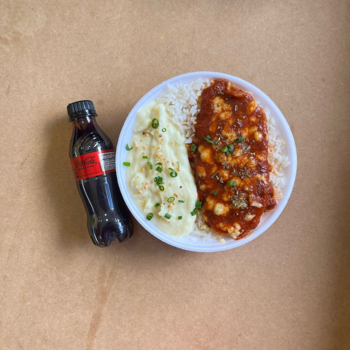 Marmita com delicioso filé de frango parmegiana (empanado na massa crocante coberto com molho de tomates e queijo) acompanhado de arroz branco e purê de batatas inglesas. Acompanha refrigerante pet Coca Cola Zero sem açúcar bem gelado. Marmita indicada para 01 pessoa.