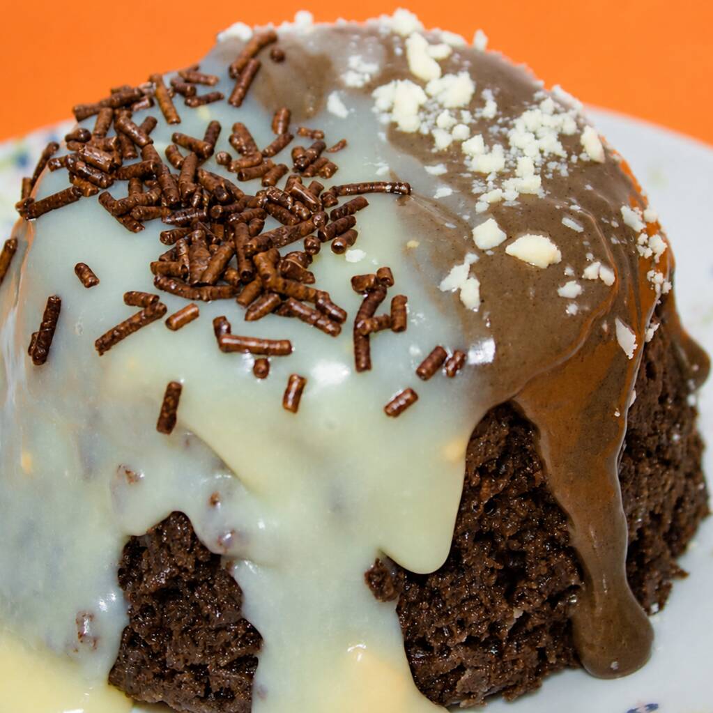 Massa de chocolate macia e fofinha, coberta com uma combinação irresistível de brigadeiro branco e brigadeiro de chocolate, finalizada com granulado crocante e raspas de chocolate branco. Receba seu bolo quentinho e aproveite cada pedaço!