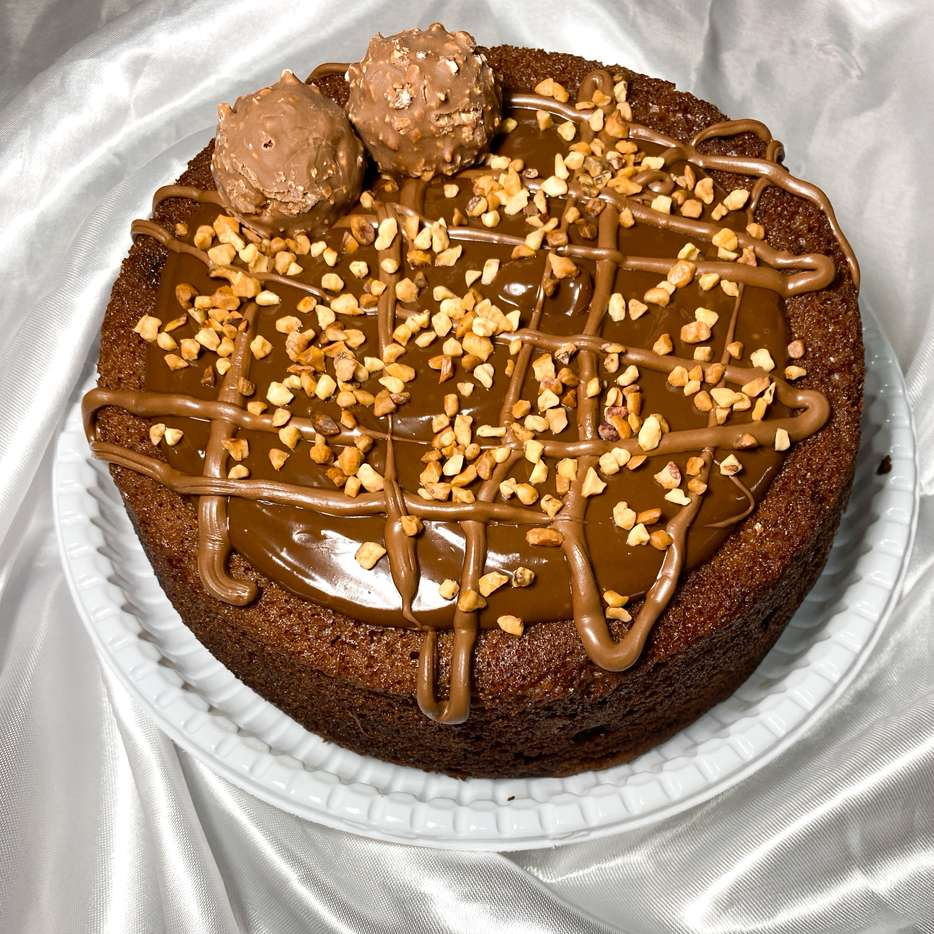 Massa de chocolate, recheada com Nutella, com cobertura de brigadeiro cremoso, finalizado com castanhas, Nutella e bombom ferrero rocher.