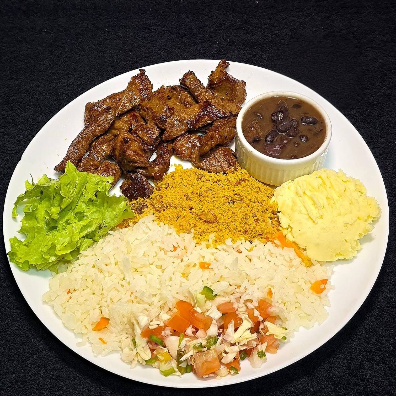 Suculentos pedaços de Filé Bovino passados na chapa (230g), acompanhados com arroz temperado caseiro, feijoada especial, farofa super crocante, generosa porção de batata frita e vinagrete.