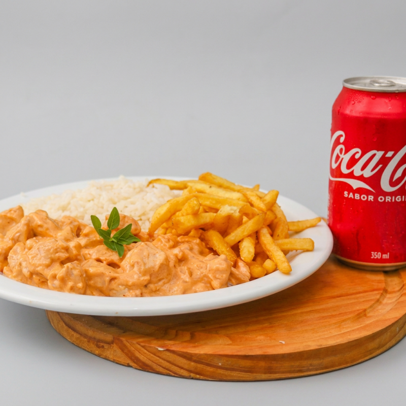 Delicie-se com o nosso Strogonoff de Frango, inspirado na receita tradicional da vovó. Este prato é meticulosamente preparado com especiarias escolhidas a dedo, resultando em um sabor incrivelmente autêntico e irresistível. Acompanha um arroz branco bem soltinho, perfeito para complementar o molho do strogonoff, e batatas fritas crocantes que adicionam uma textura deliciosa ao prato. Além disso, ganhe uma lata de Coca Cola como cortesia para harmonizar com a refeição. Uma escolha popular da categoria 'Os mais pedidos do !', esse prato é uma verdadeira festa de sabores!