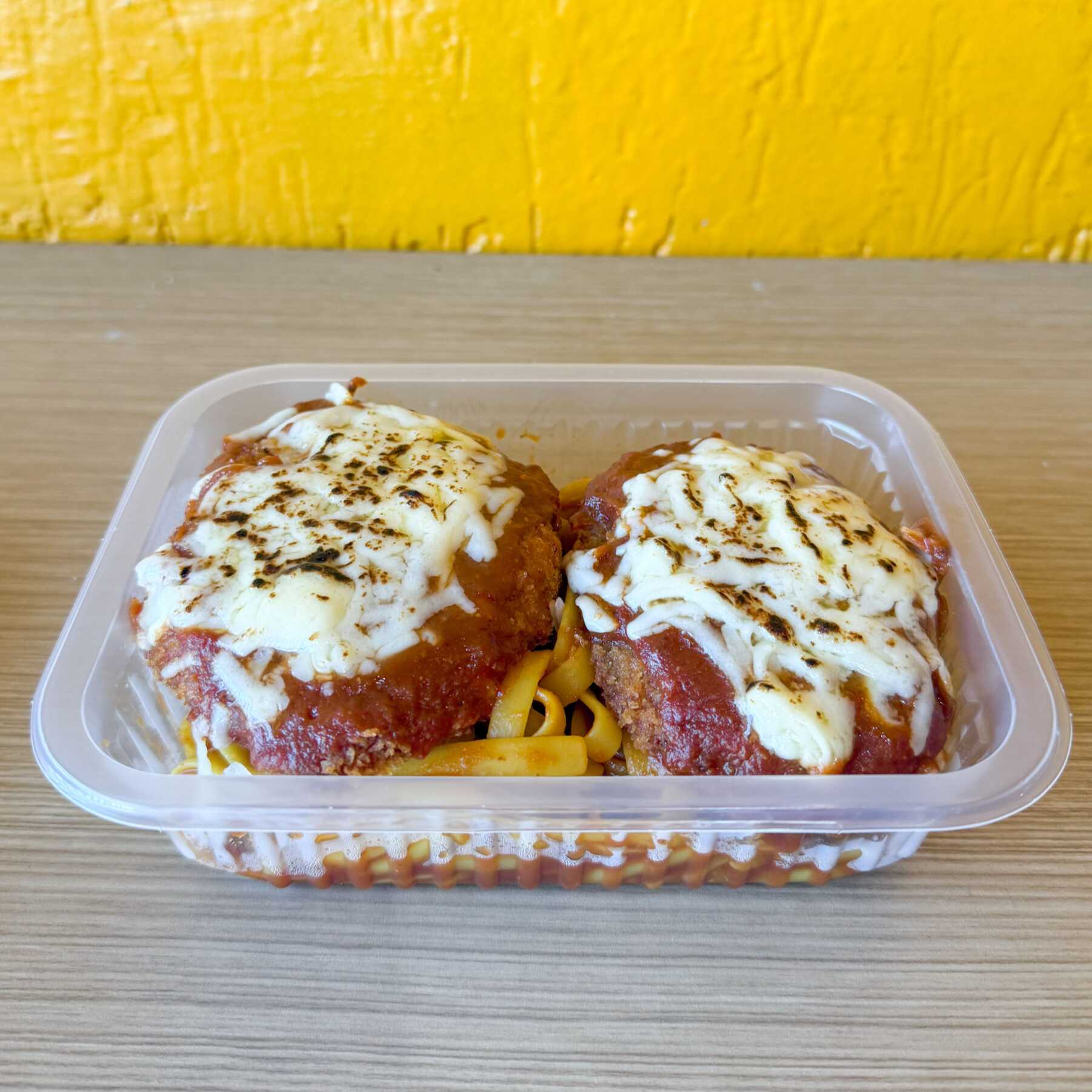 Macarrão fettuccine com molho de tomate acompanhado de frango à parmegiana com queijo gratinado. Combinação clássica que sempre agrada.
