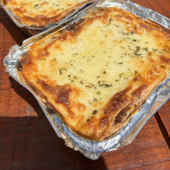 Lasanha bolonhesa caseira, bem recheada com carne moída temperada, presunto, molho de tomate e muito queijo gratinado. Servida quentinha na marmita, perfeita para o seu almoço.