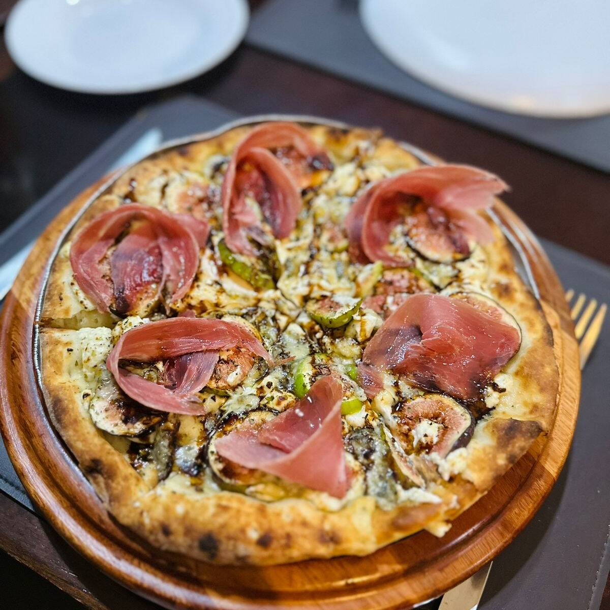 Massa regada com azeite, cream cheese, figos maduros e frescos, gorgonzola e orégano ao forno, finalizada com presunto parma, redução de balsâmico e mel.