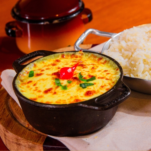 Escondidinho preparado a base de mandioca recheado com costela bovina assada na brasa e requeijão, servido com arroz branco e batata chips.