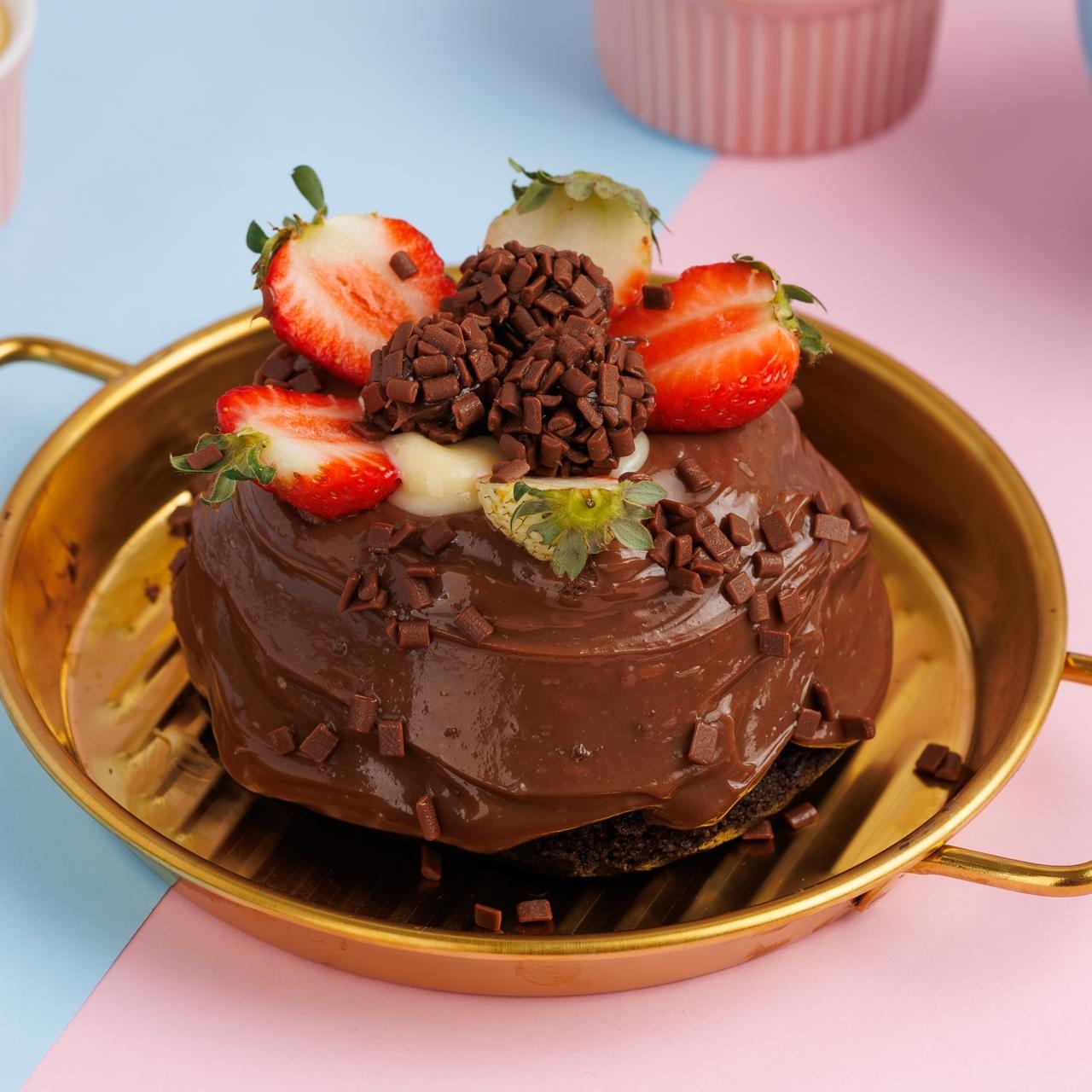 Lindo bolinho feito com massa de chocolate cobertura de brigadeiro no meio creme de Ninho decorado com morangos e brigadeiros