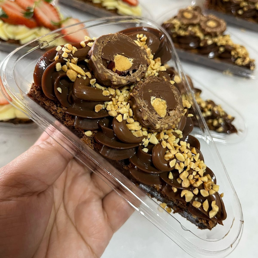 Fatia de brownie com recheio de chocolate, Nutella, amendoim e Ferrero Rocher no topo