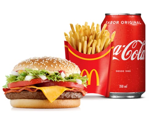 Um hambúrguer (carne 100% bovina), bacon, alface americana, cebola, queijo processado sabor cheddar, tomate, maionese, ketchup, mostarda e pão com gergelim, acompanhamento e bebida.