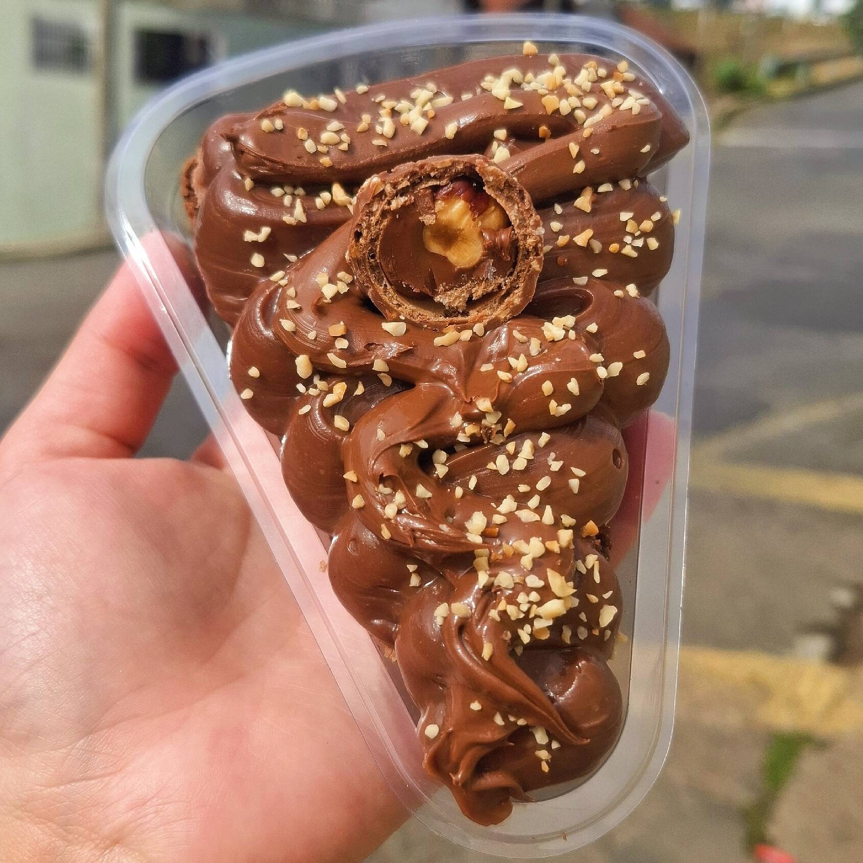 Fatia de brownie com cobertura de brigadeiro 70% cacau, nutella, castanha de caju e bombom ferrero