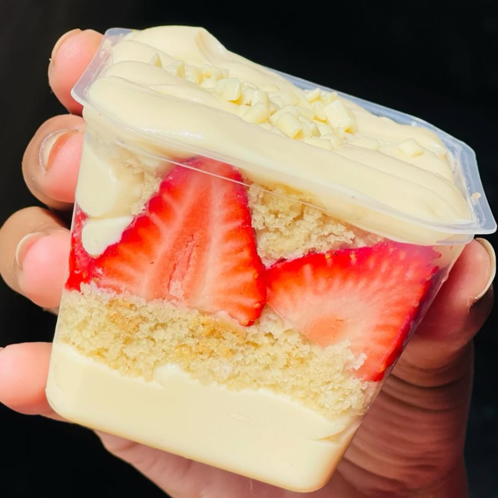 Brigadeiro cremoso de Ninho, bolo de massa branca esfarelado, molhado com calda de leite condensado, morangos picados e finalizado com morango.