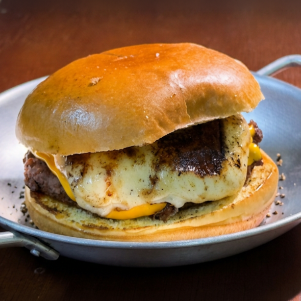 Pão brioche, 120g de hambúrguer, maionese da casa, queijo cheddar derretido com uma crosta de queijo.