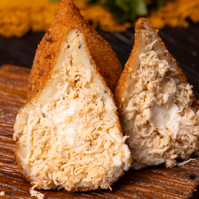 Crocante por fora, cremosa por dentro. Nossa coxinha passa por um processo de fabricação próprio que vai desde a massa que fazemos até o frango desfiado, cozido por horas e muitíssimo bem temperado. Para finalizar, temos um toque de Requeijão cremoso que se mistura com o delicioso recheio.