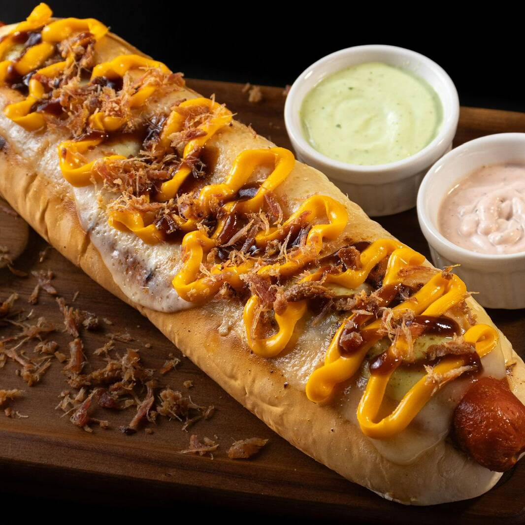 PÃO DE BATATA DE 30CM APROXIMADAMENTE, 2 SALSICHAS, KETCHUP,MOLHOS, QUEIJO MUSSARELA MAÇARICADO, CHEDDAR CREMOSO, BARBECUE E BACON
