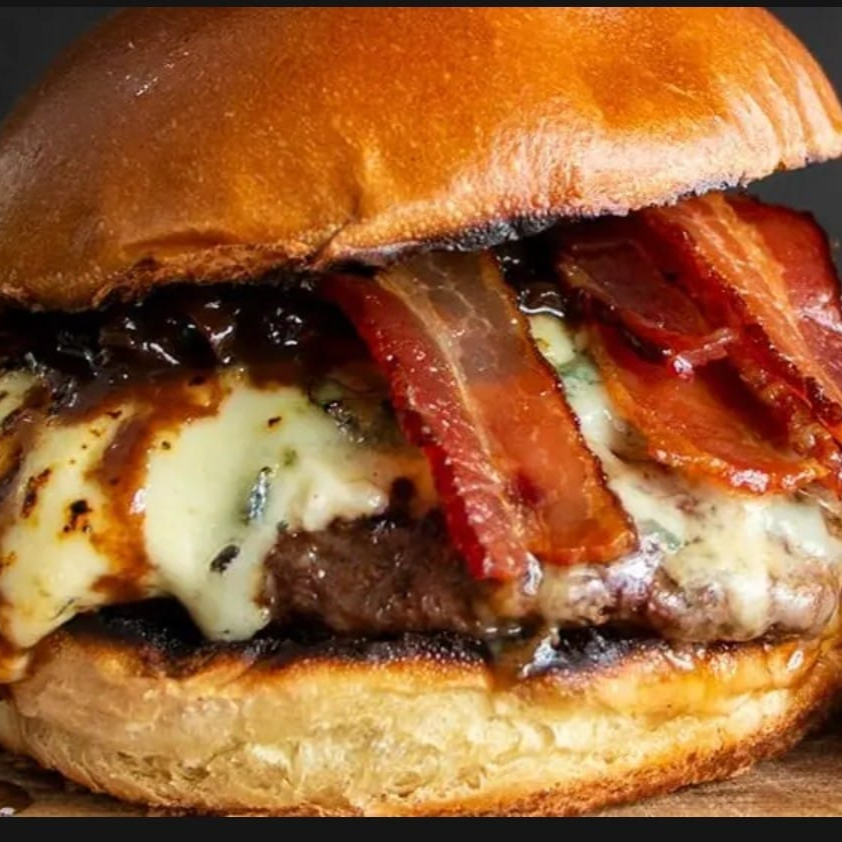 Burguer de 180grs grelhado na parrilla, coberto por queijo gorgonzola maçaricado, fatias de bacon grelhado e finalizado com a deliciosa cebola caramelizada na cerveja preta no pão brioche