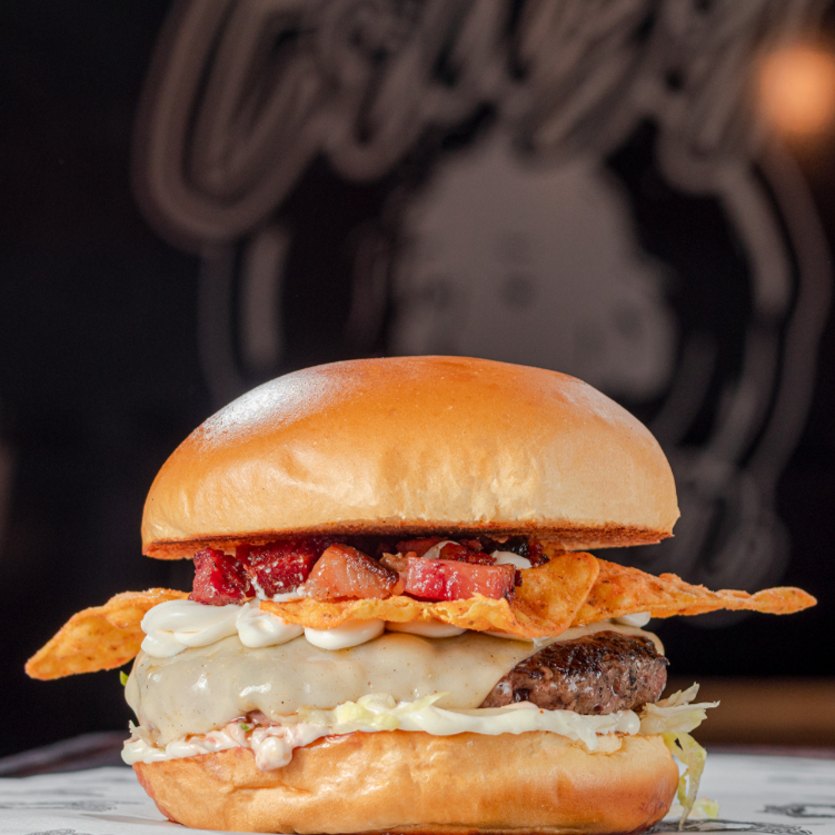 Pão brioche com hambúrguer artesanal de 150g, queijo muçarela derretido, e cream cheese com bacon crocante em cubos. Finalizado com Doritos inteiros para uma crocância surpreendente e maionese especial da casa. Uma explosão de sabores única para quem busca algo diferente!
