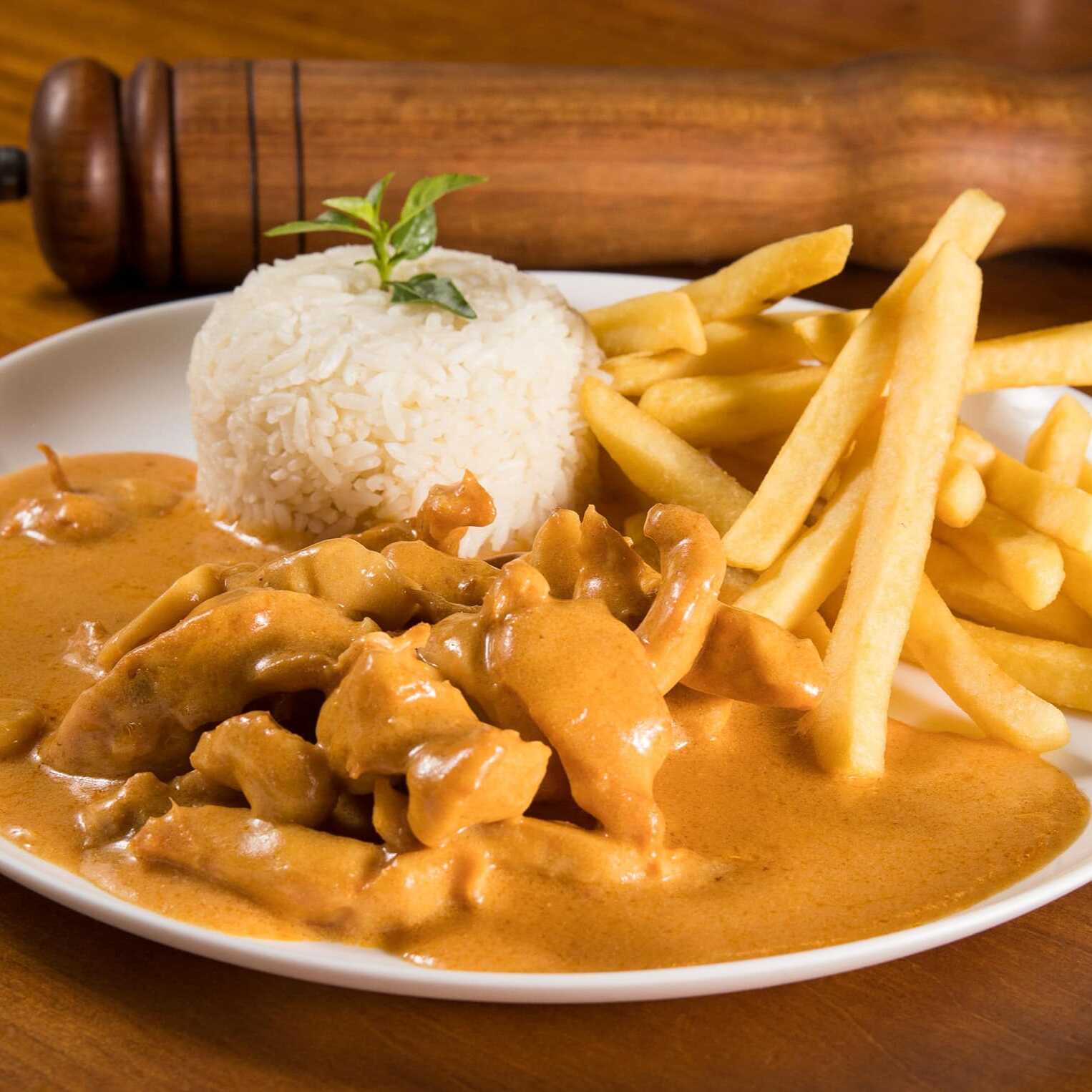 Strogonoff de frango com arroz e batata frita.