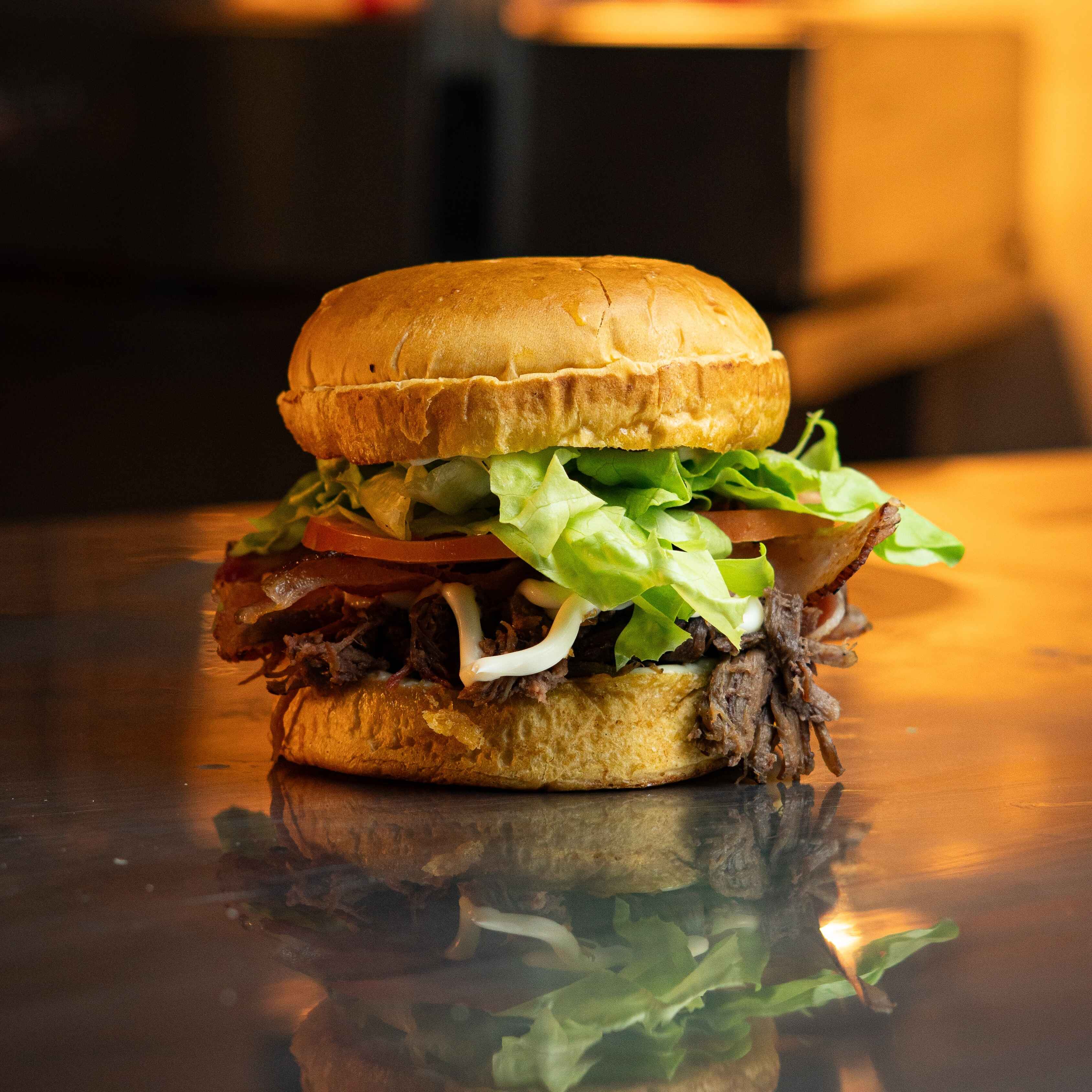 Pão brioche, Costela desfiada, catupity, bacon, alface e tomate.