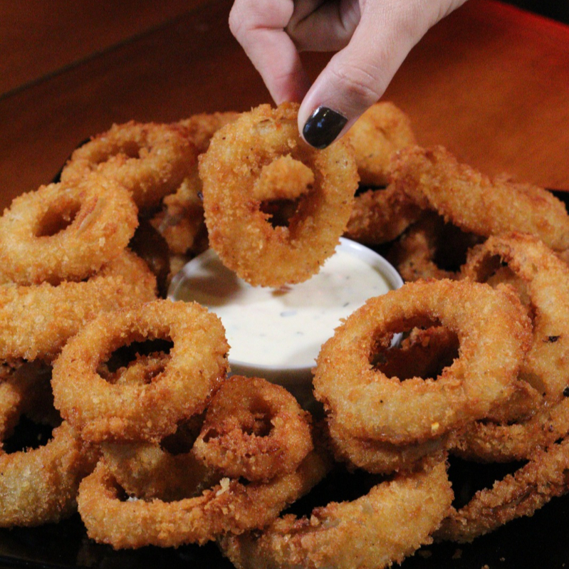 Anéis de cebola crocantes, servidos com molho Ranch da casa, no autêntico On Fire style