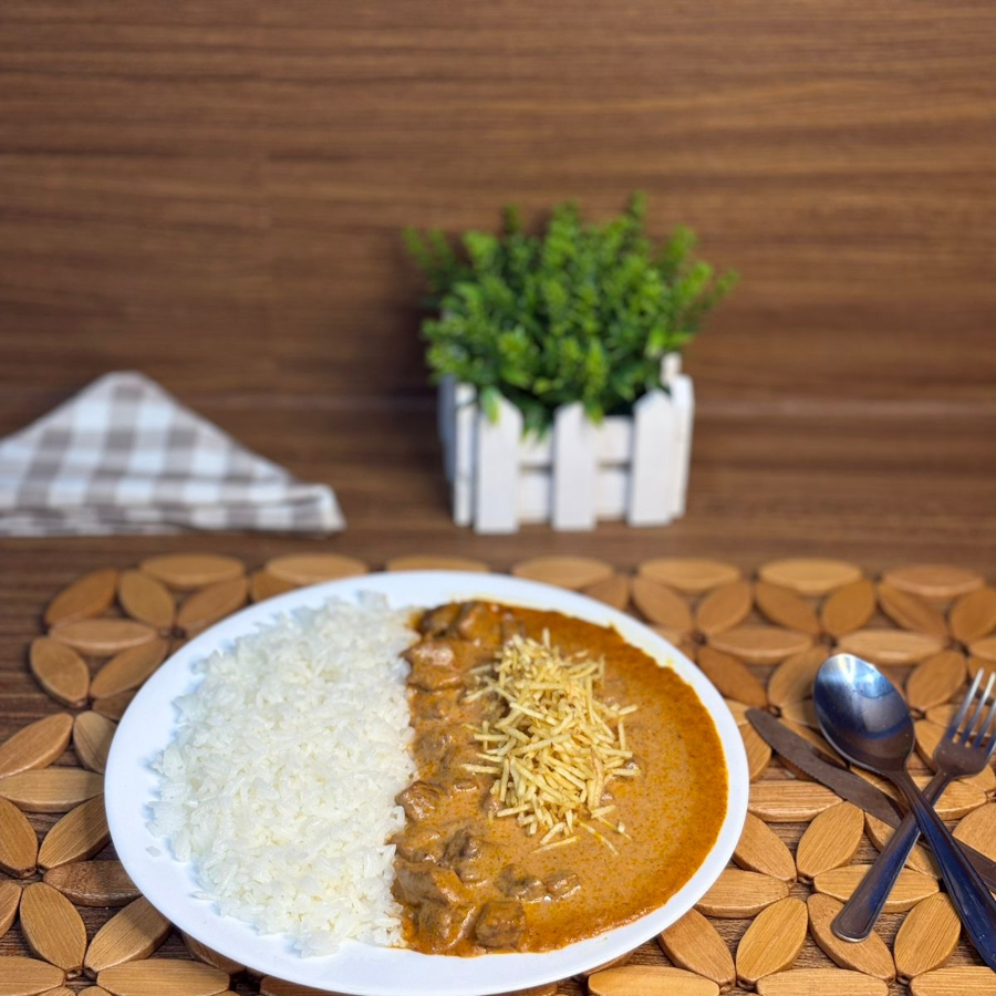Cubos de carne em um delicioso molho de estrogonofe, servidos com arroz e batata palha.