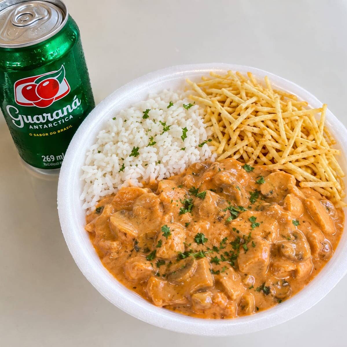 Strogonoff cremoso acompanhado de arroz soltinho e batata palha crocante. Acompanha Guaraná lata 269ml. Marmita Aproximadamente 500g