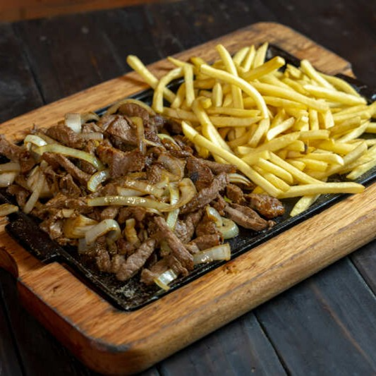 Um clássico irresistível! Steak em tiras, envolto em cebolas caramelizadas e temperado com um blend especial de especiarias. Acompanhado de batata ou mandioca frita, você decide como saborear essa delícia