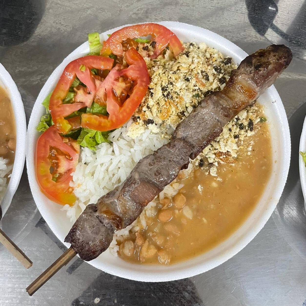 Deliciosa jantinha caseira. Arroz, feijão, salada de alface e tomate, farofa especial e um espetinho cotra file. Aproximandamente 480g. Acompanha molho de alho.