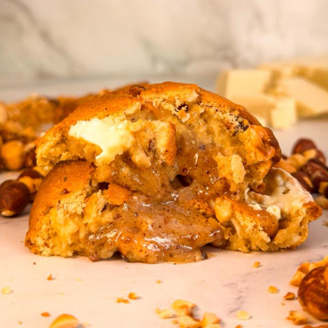 Cookie com bastante chocolate branco e avelãs torradas na massa. Recheado com nosso creme bueno artesanal, feito com pasta de avelãs, chocolate branco e leite em pó. Inspirado no Kinder Bueno White.